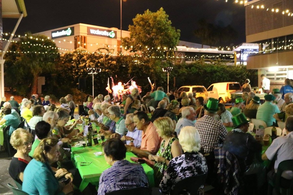 Long tables of locals under festoon lights at a St Patrick's night at the Hub